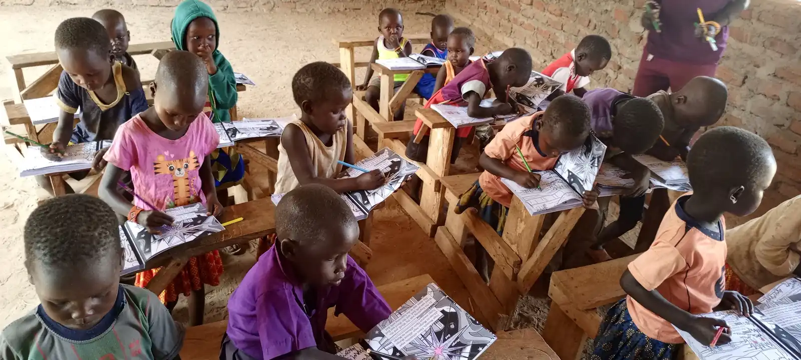 A classroom of children bent over their Bible workbooks